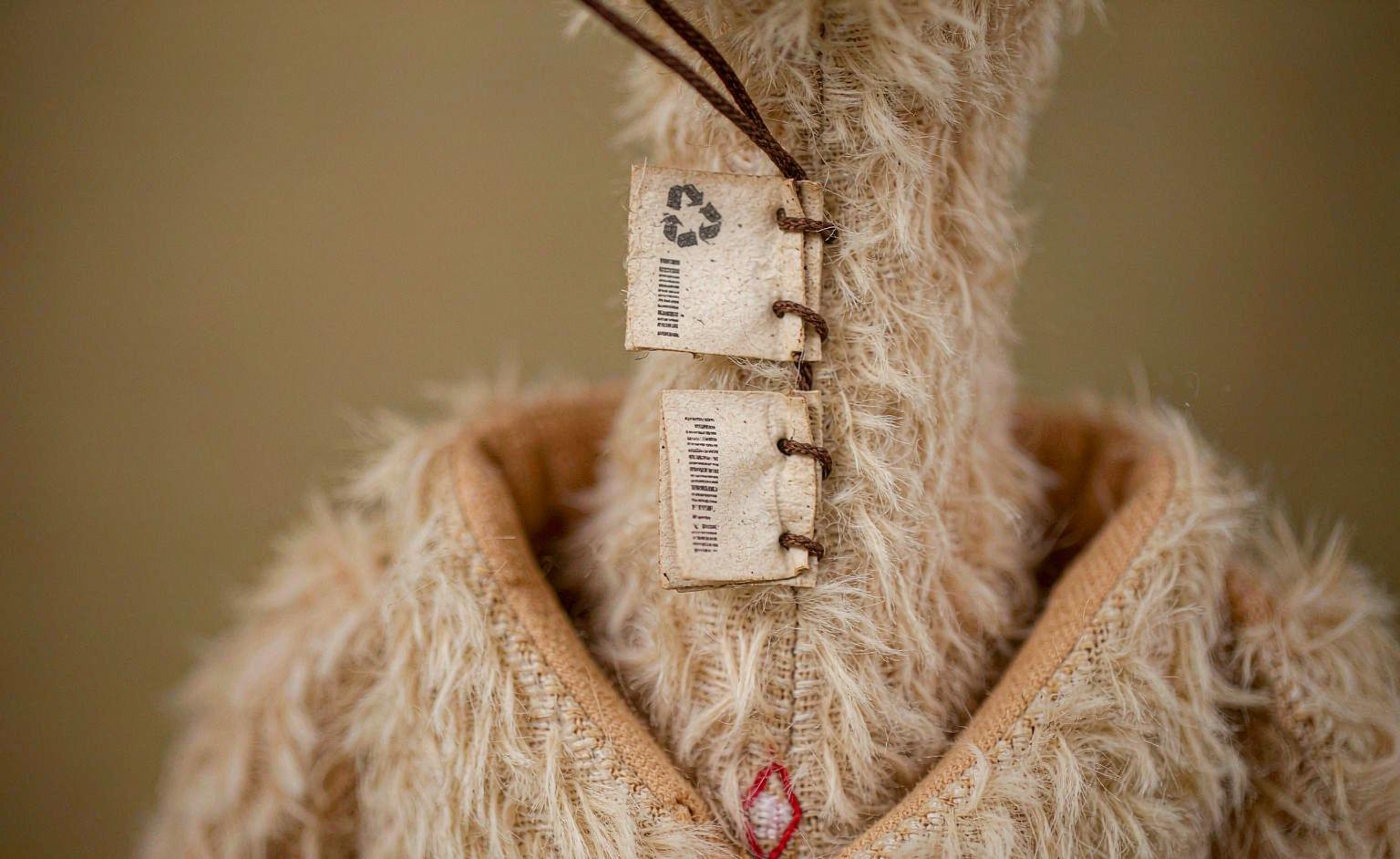 Close-up of certification tags — GOTS, OEKO-TEX, and GRS — stitched onto a plush toy seam
