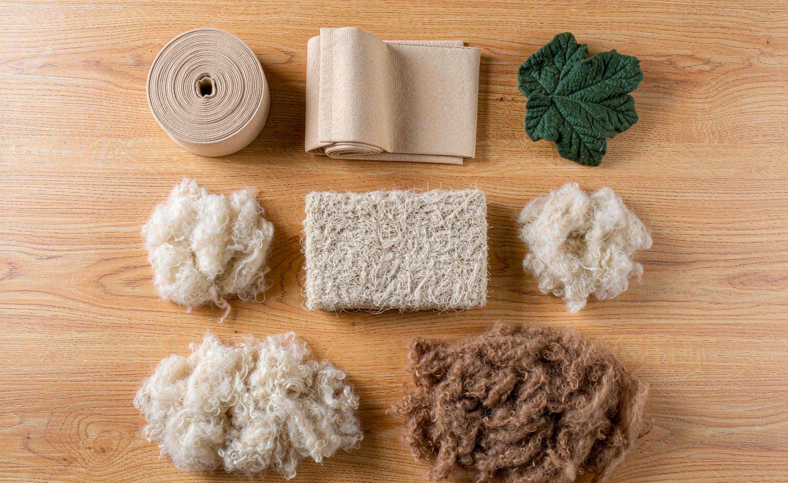 A flat lay of eco-friendly plush materials: recycled polyester fabric, organic cotton, and natural fiber fill
