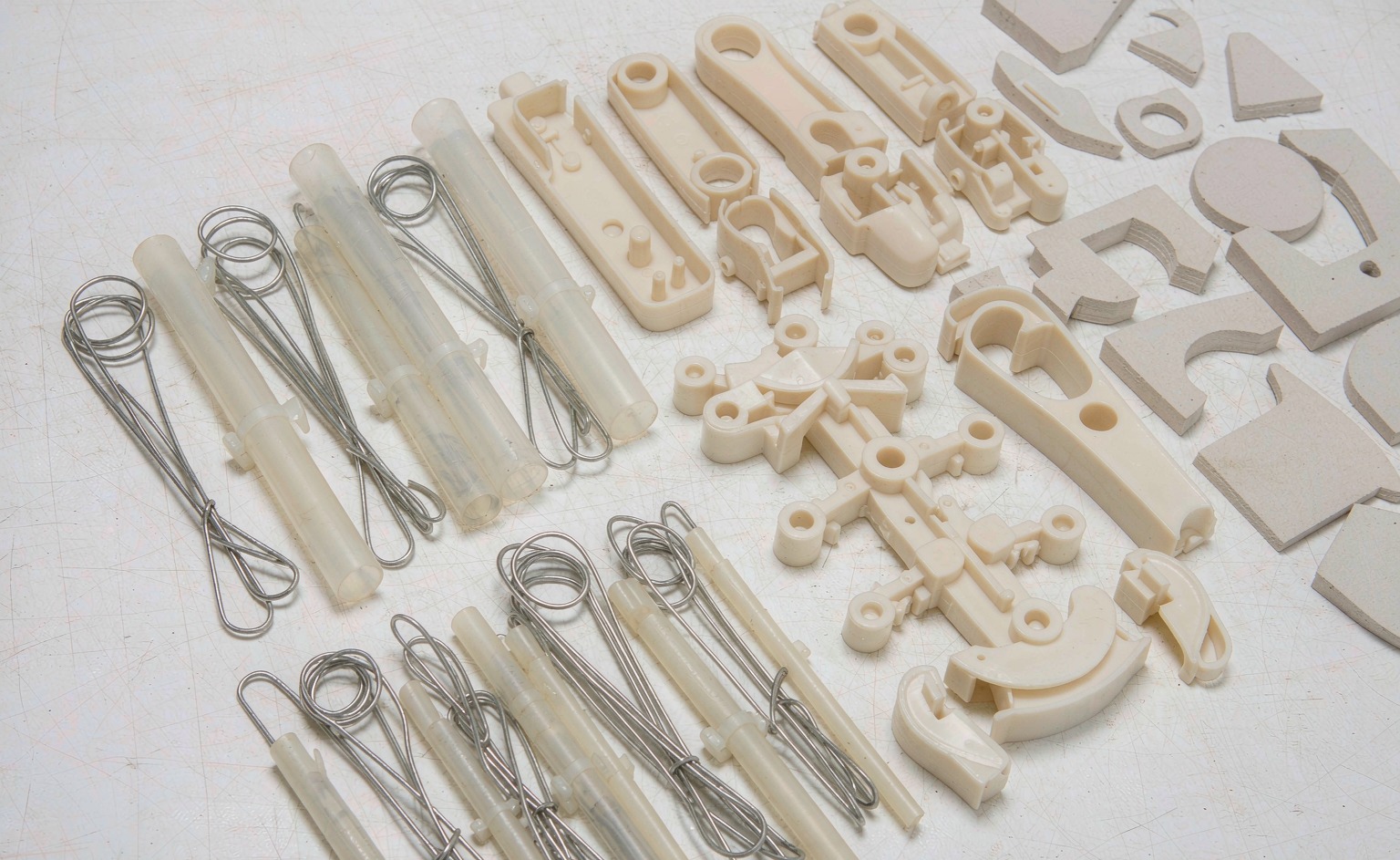 Internal structure components laid out on a workbench - wire armatures, plastic skeleton frames, and foam core inserts of various shapes