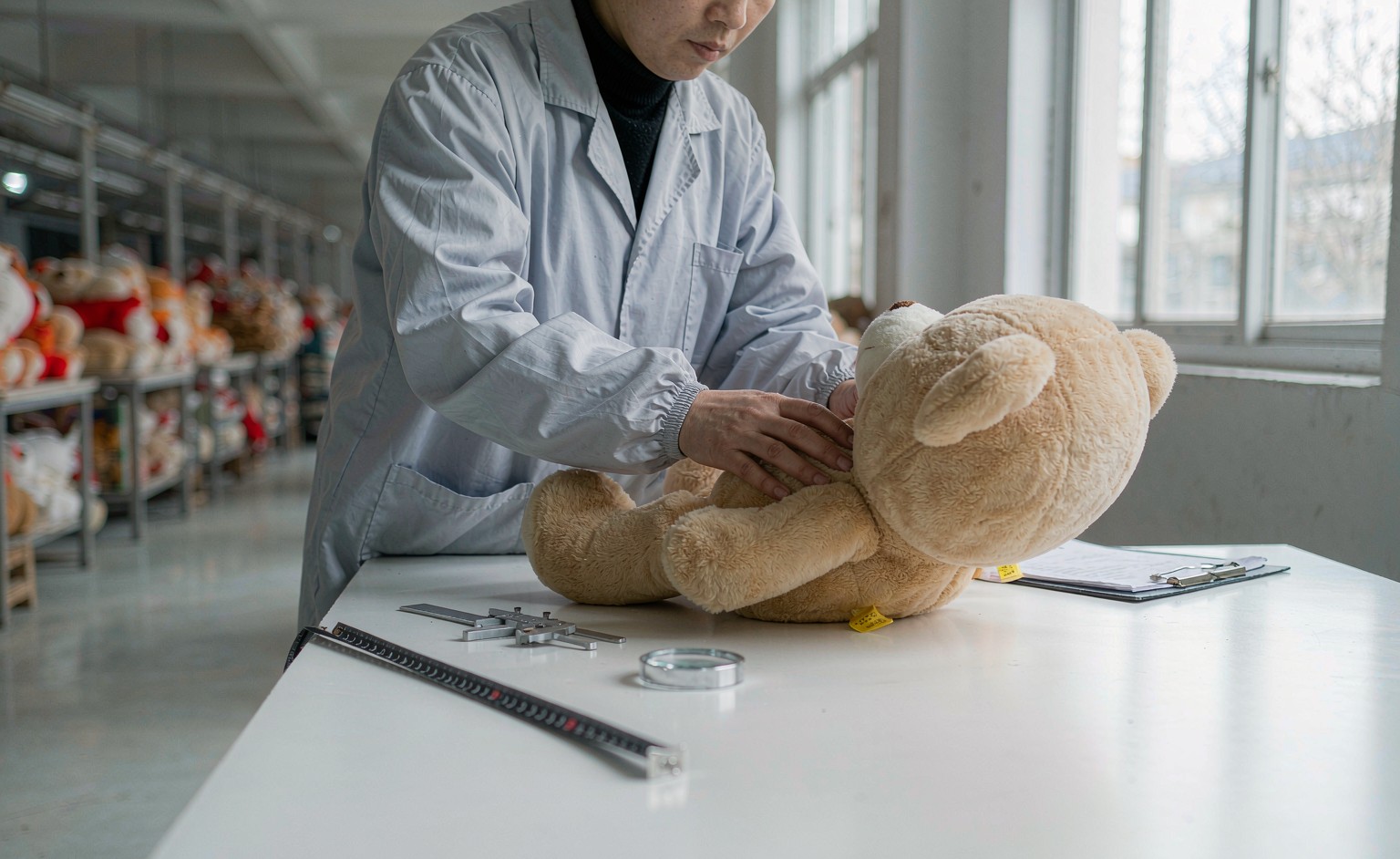 An inspector examining plush toy seams and stitching on a production line