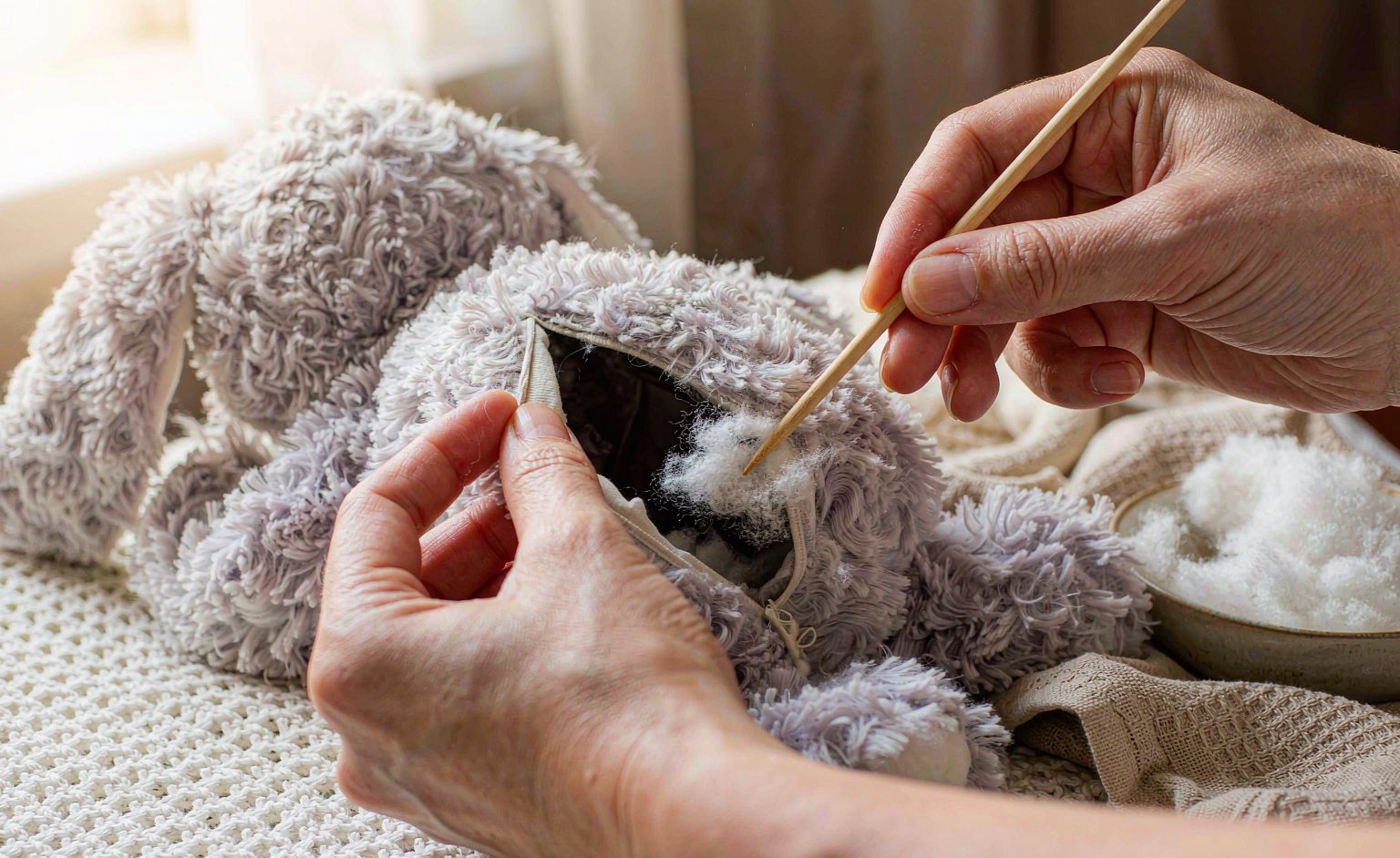 Adding polyester fibrefill to restore the shape of a worn plush toy