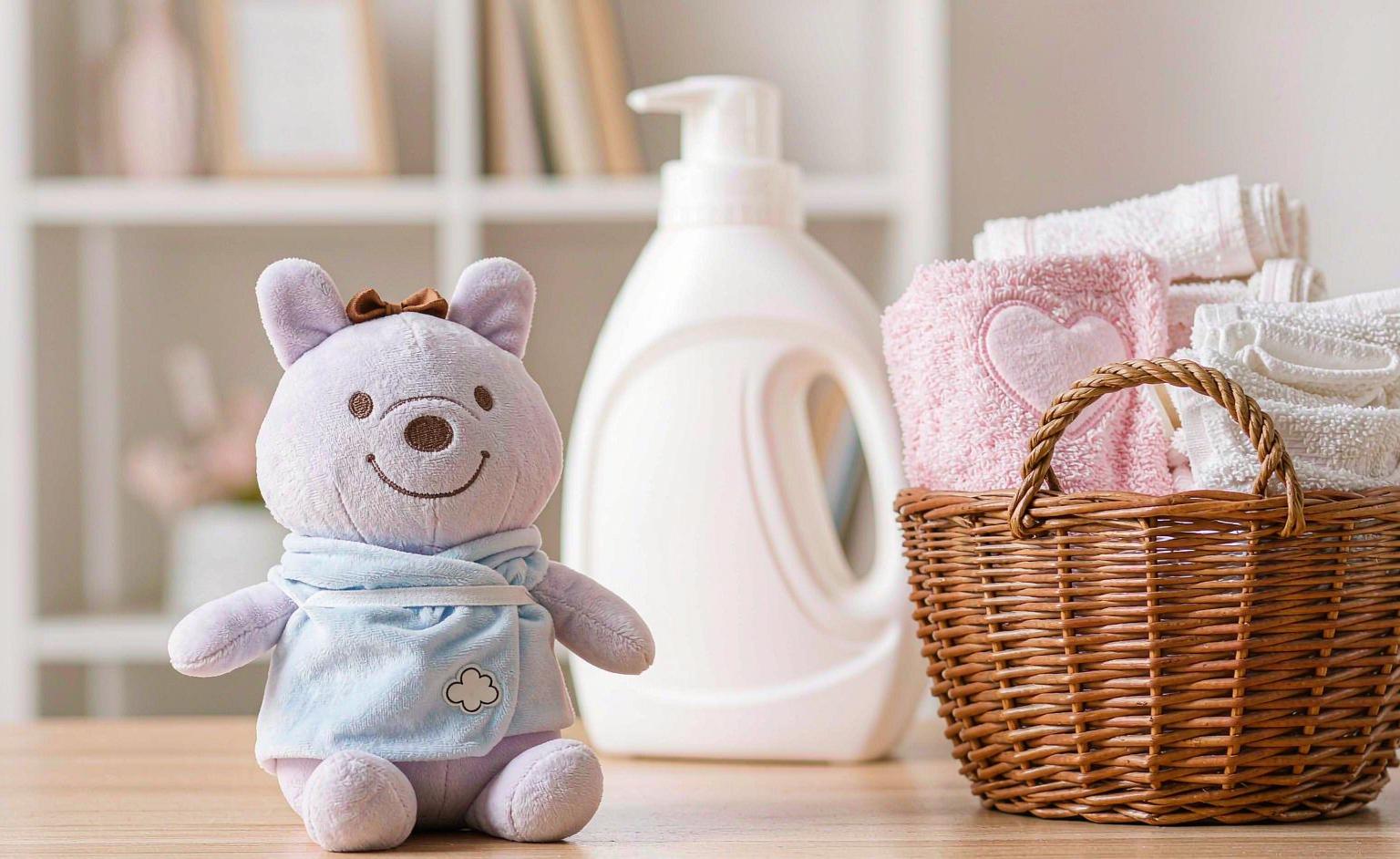 A clean soft plush toy placed in a laundry basket with gentle detergent nearby